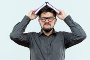 Homem frustrado com livro na cabeça.